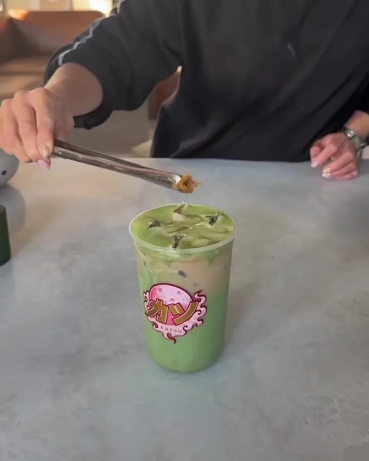 A matcha drink with the Katsu sticker, finished on the counter