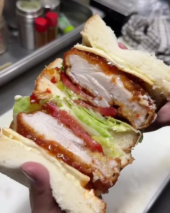 The OG Sando held up in the kitchen, crumbed chicken under thick milk bread