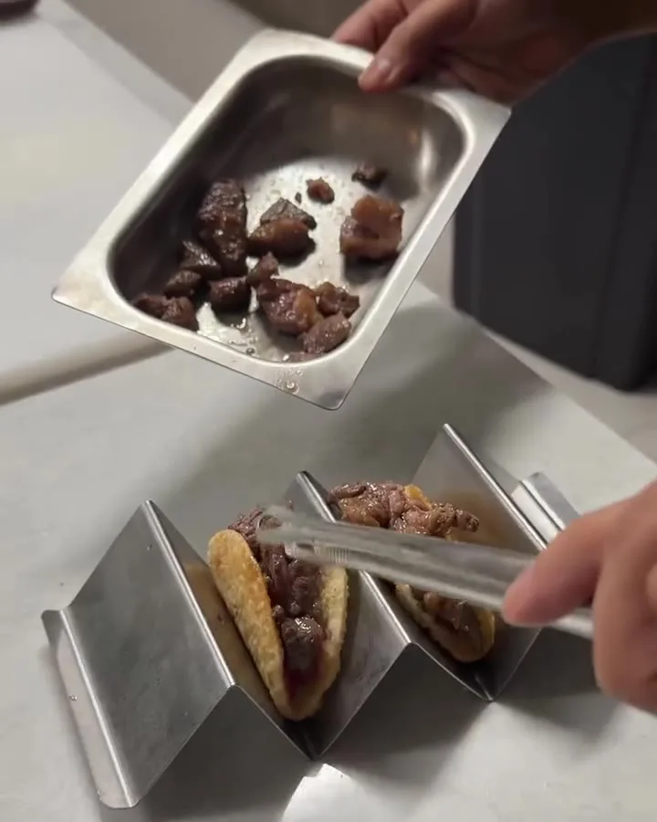 Tacos lined up in steel holders, ready to go out