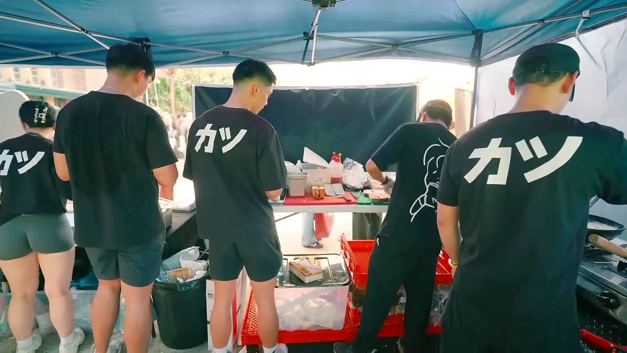 The crew in their black カツ tees working the stall at a pop-up
