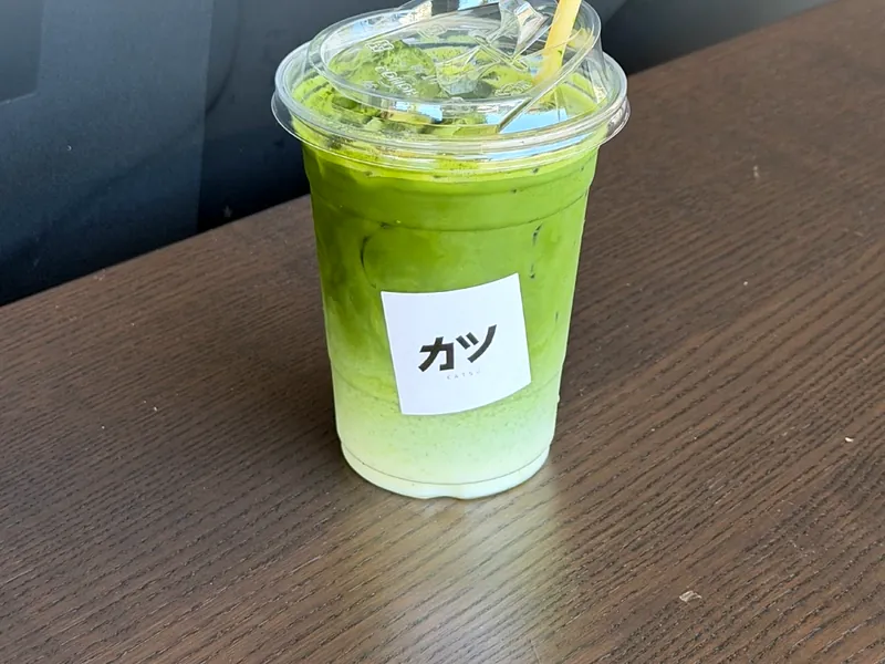 An iced jasmine matcha with the カツ sticker on the cup
